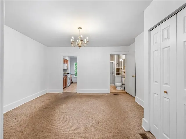 an empty room with chandelier fan and windows