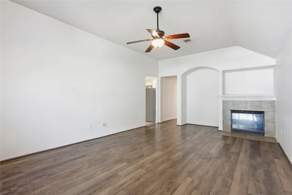 a view of an empty room with wooden floor fireplace and a window