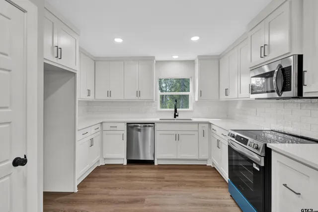 a kitchen with appliances cabinets and a wooden floor