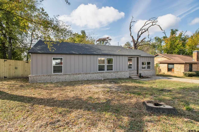 a view of a house with a yard and large tree