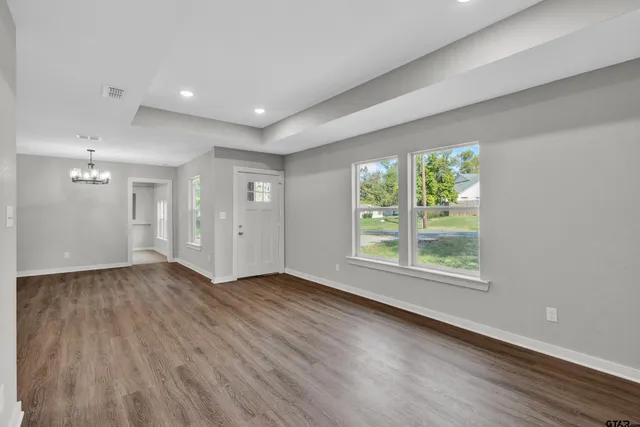 a view of an empty room with window and wooden floor