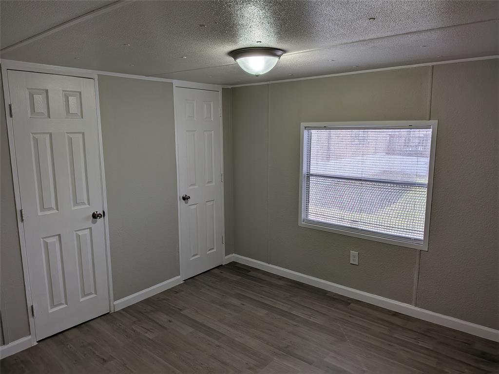 563 John Ross Road Wylie, TX 75098 - Photo 6 of 13 Unfurnished bedroom featuring a textured ceiling and dark wood-type flooring