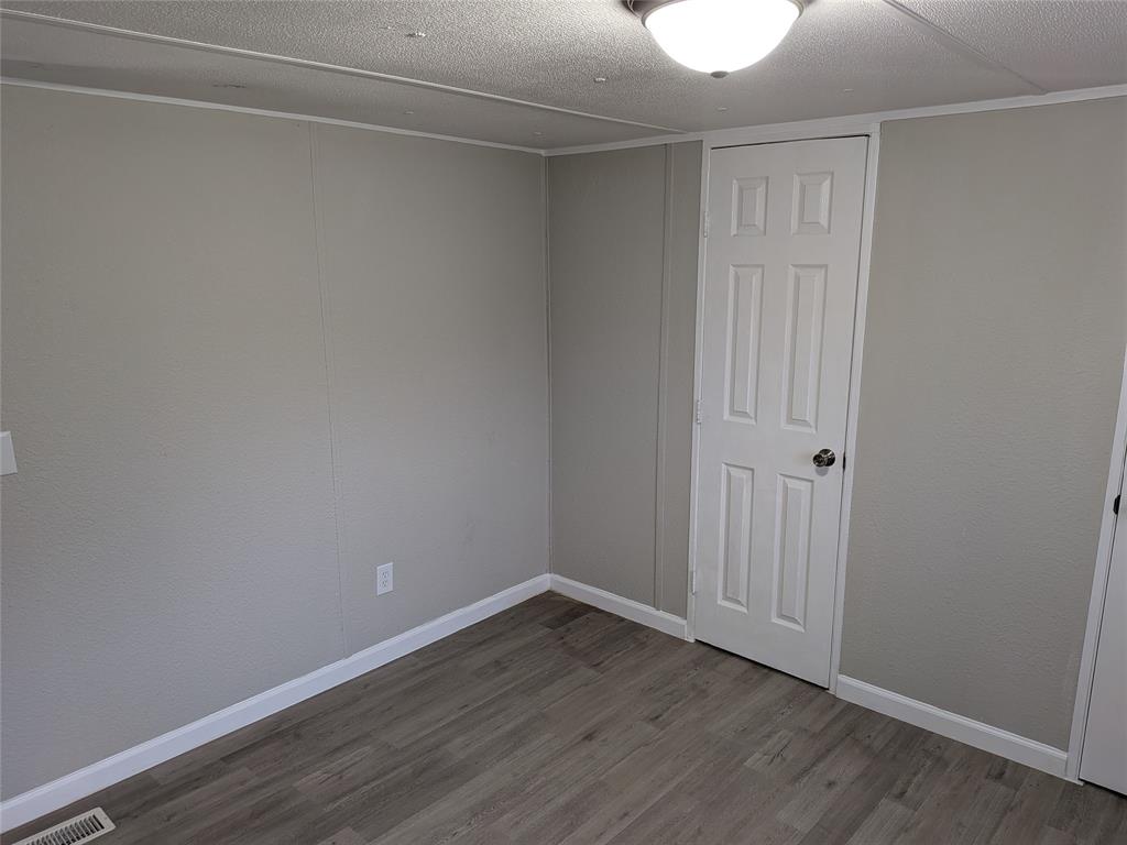 563 John Ross Road Wylie, TX 75098 - Photo 7 of 13 Unfurnished bedroom featuring wood finished floors and a textured ceiling