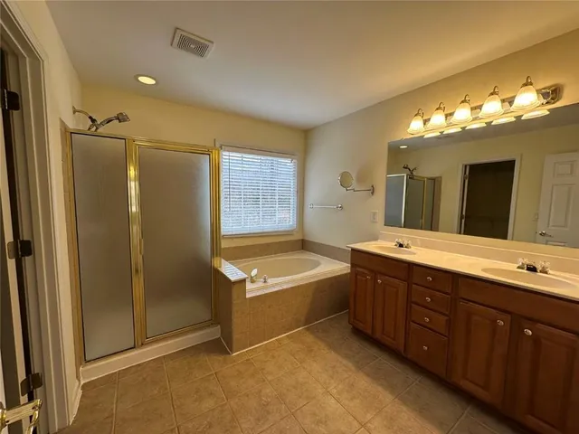 a spacious bathroom with a tub sink and mirror