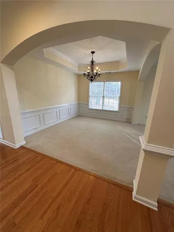 an empty room with wooden floor chandelier and windows