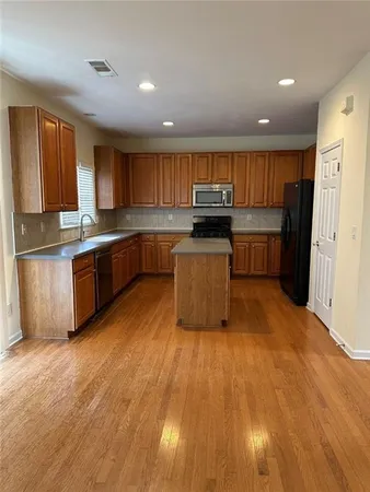 a kitchen with stainless steel appliances granite countertop a sink a stove top oven a refrigerator with island and chairs