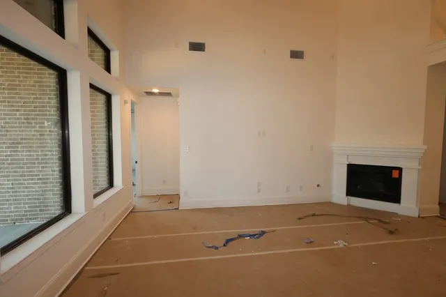a view of an empty room with a fireplace and a kitchen