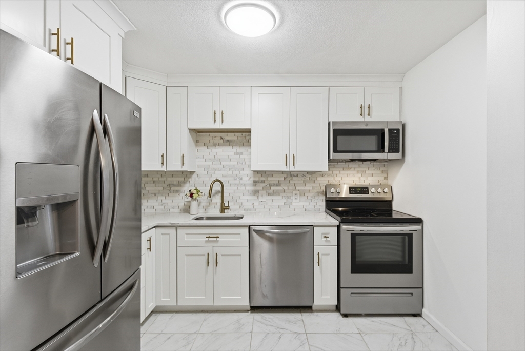 4 Erick Road, Unit 90 Mansfield, MA 02048 - Photo 12 of 30 a kitchen with cabinets stainless steel appliances and sink