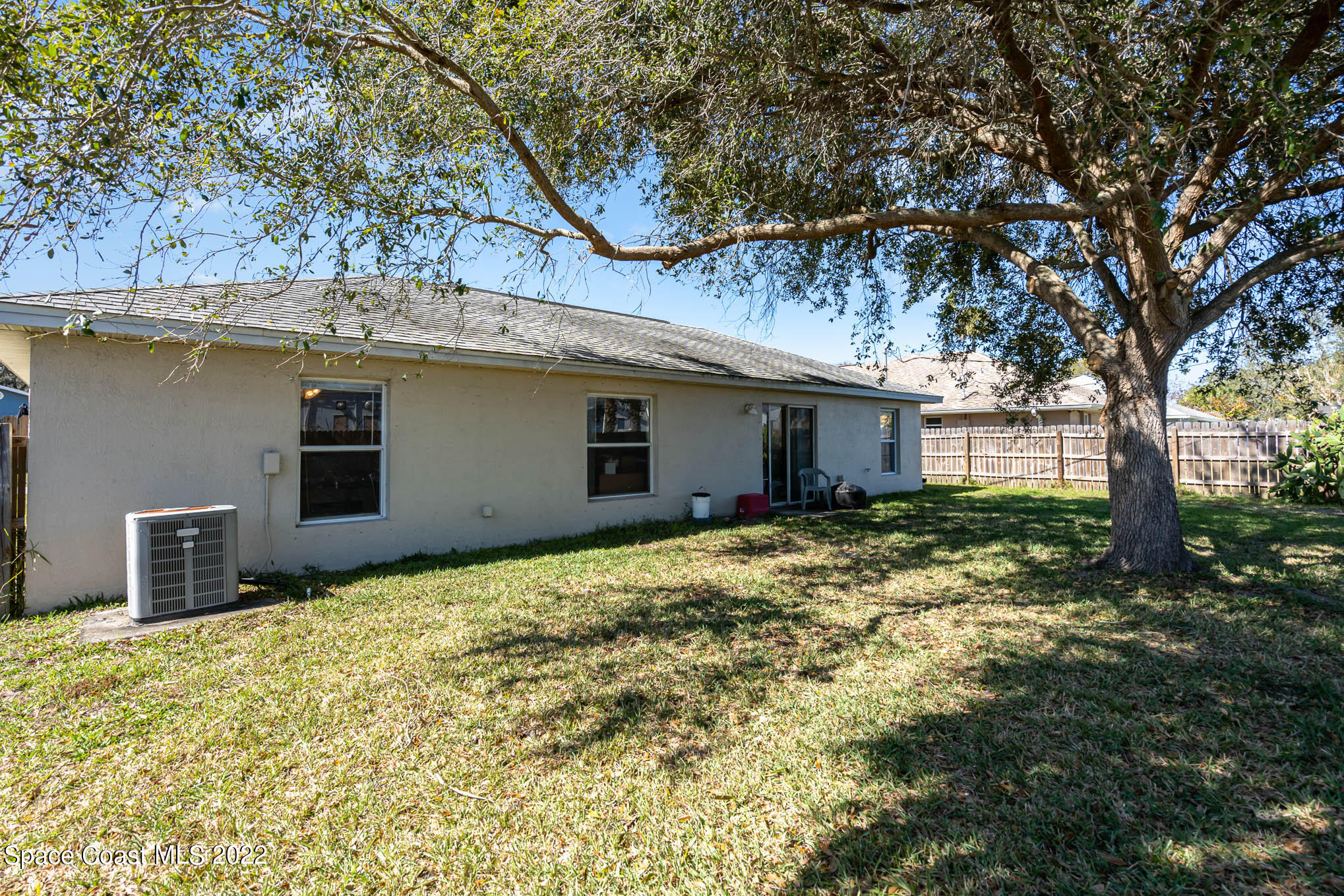 1247 Van Tassel Trail Palm Bay, FL 32905 - Photo 29 of 31 a backyard of a house with large trees and table and chairs
