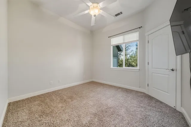 an empty room with a chandelier fan and windows