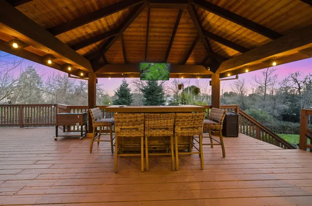 a patio with wooden floor a yard a table and chairs