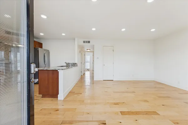 a view of empty room with wooden floor and fan