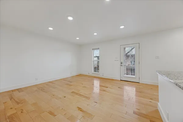 a view of an empty room with kitchen and window