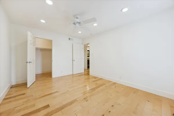 an empty room with a chandelier fan and windows