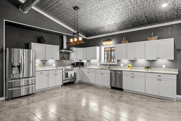 a kitchen that has a lot of white cabinets and stainless steel appliances