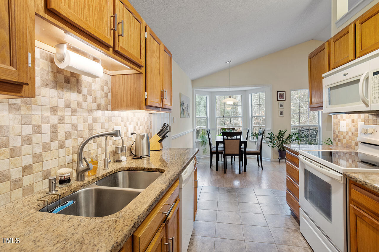 4437 Labrador Drive Raleigh, NC 27616 - Photo 16 of 25 a kitchen with stainless steel appliances a sink a counter top space and living room view
