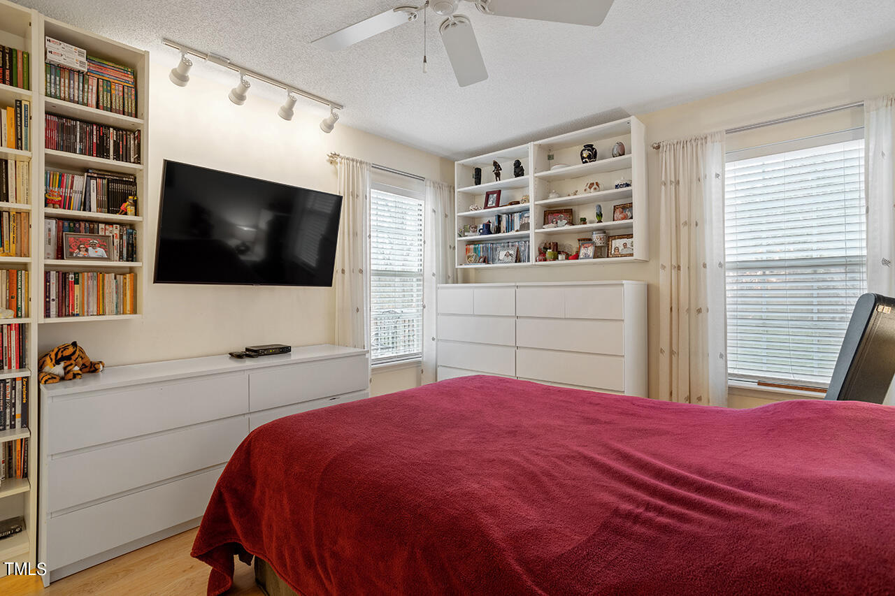 4437 Labrador Drive Raleigh, NC 27616 - Photo 18 of 25 a bedroom with a large bed a flat tv screen and a book shelf