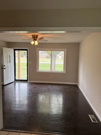 a view of an empty room with wooden floor and a window