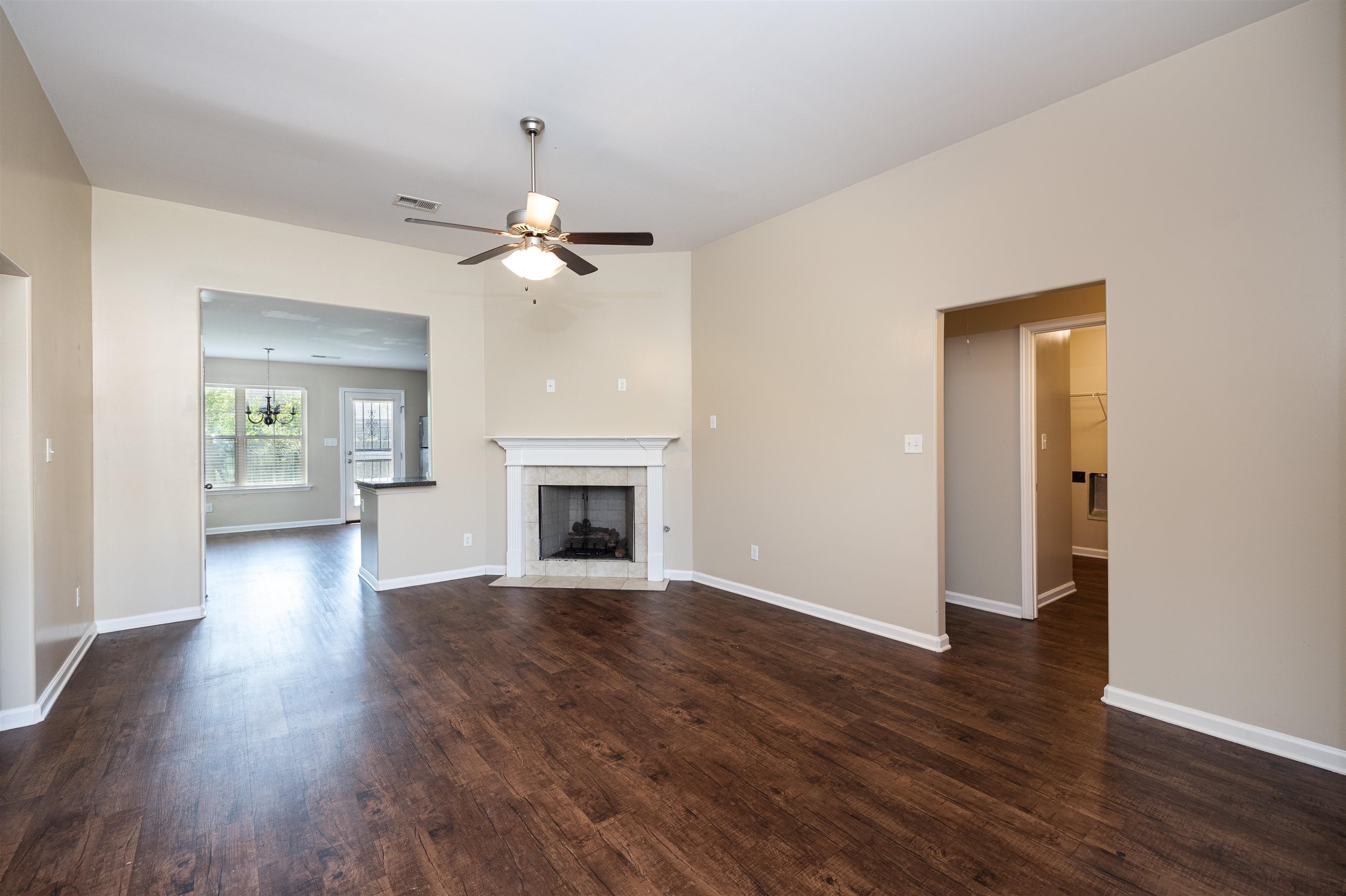 5262 Crossfield Road Memphis, TN 38109 - Photo 4 of 19 an empty room with wooden floor a ceiling fan a fireplace and windows