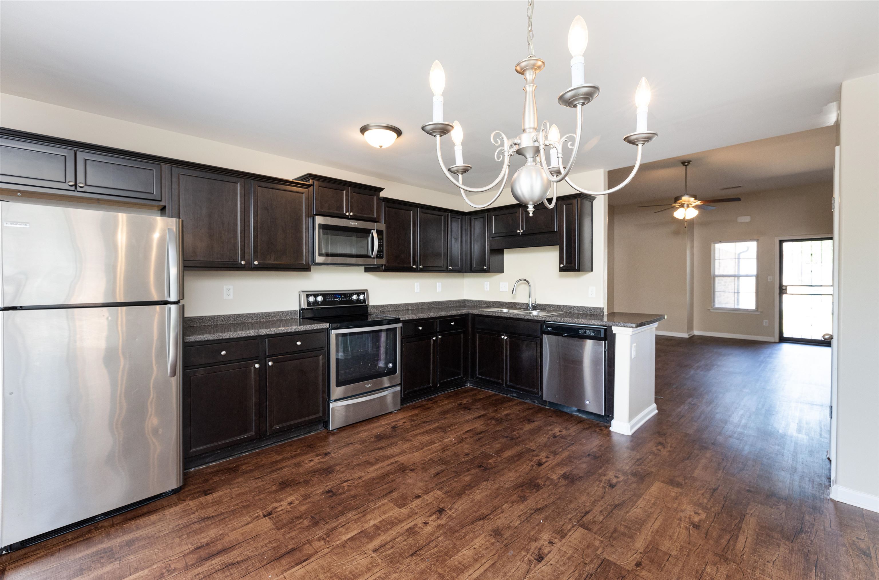 5262 Crossfield Road Memphis, TN 38109 - Photo 8 of 19 a kitchen with stainless steel appliances granite countertop a refrigerator a sink dishwasher a stove and a dining table with wooden floor