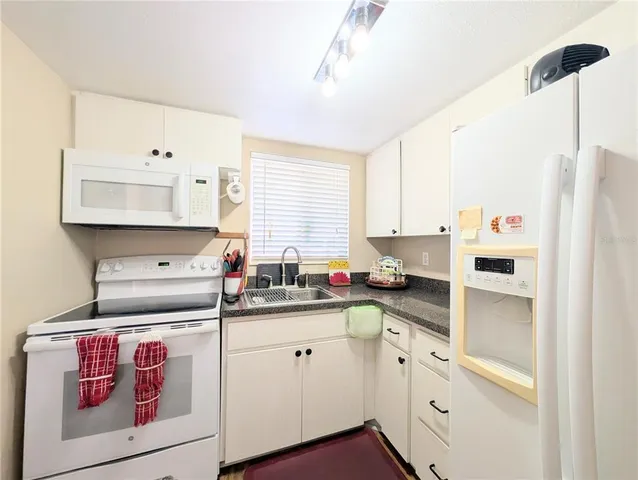a kitchen with white cabinets and white appliances