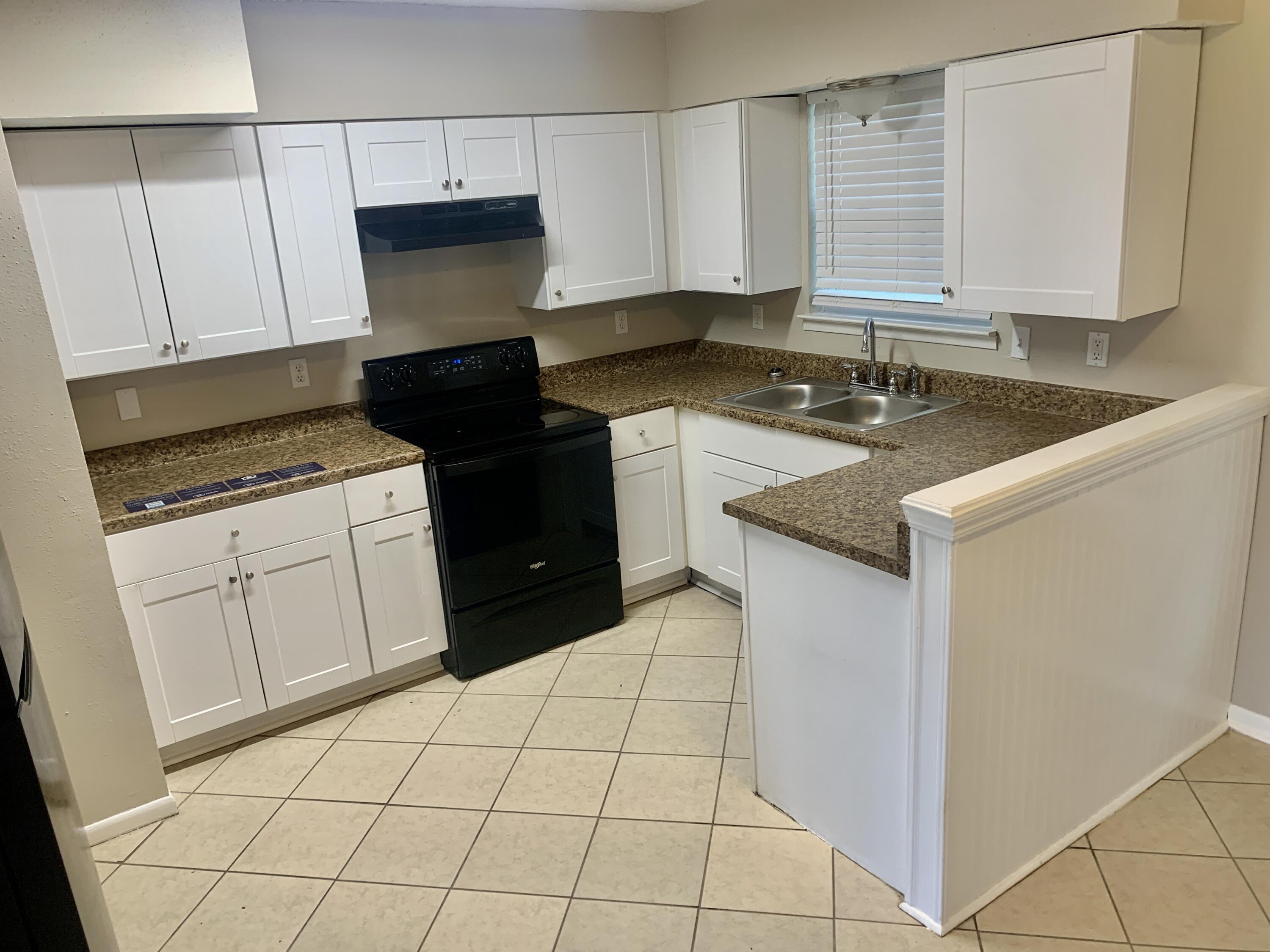 122 West 1st Avenue Crestview, FL 32536 - Photo 4 of 15 a kitchen with granite countertop white cabinets and black appliances