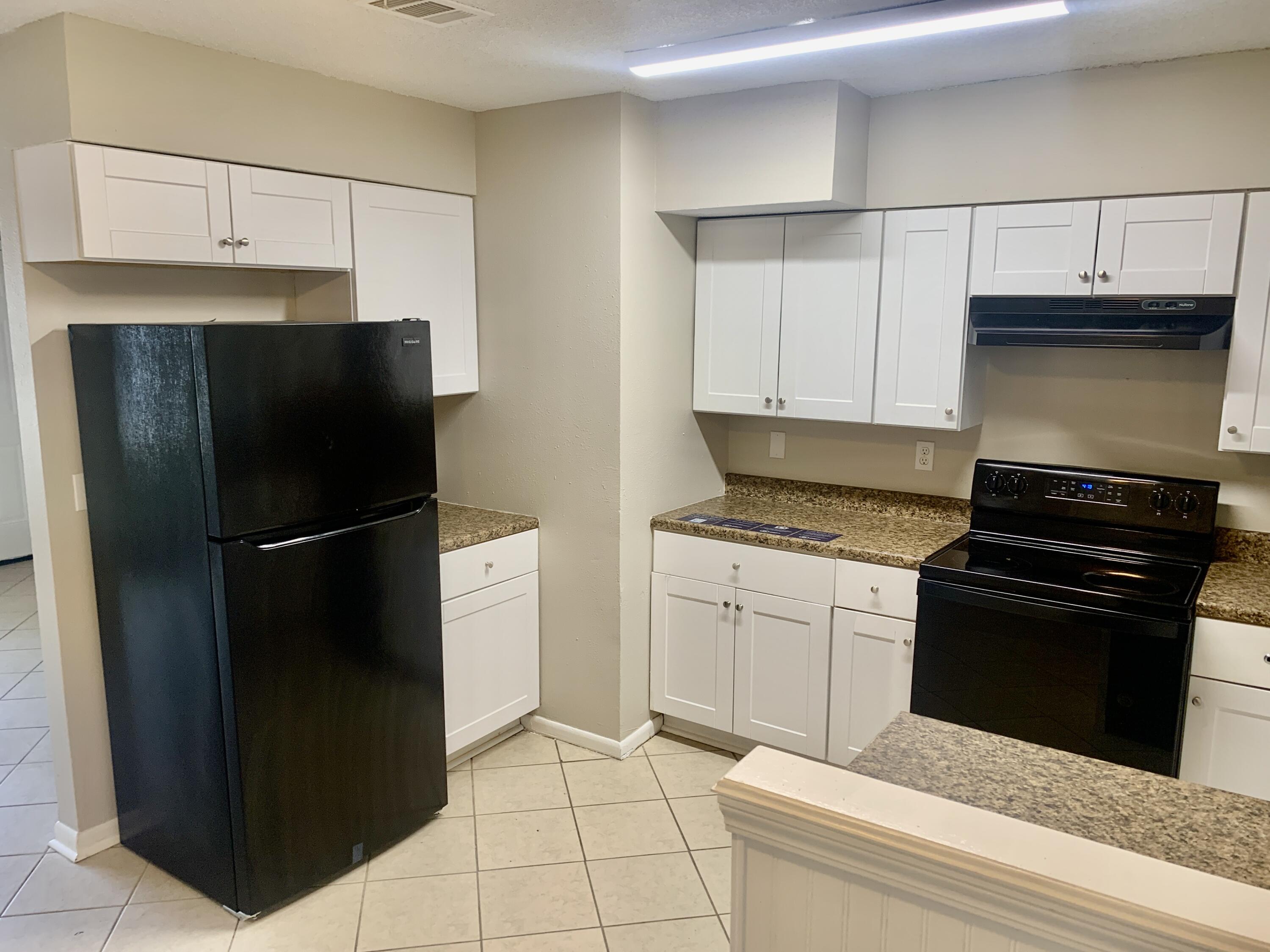 122 West 1st Avenue Crestview, FL 32536 - Photo 5 of 15 a kitchen with a refrigerator stove and cabinets