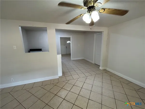 a view of an empty room and chandelier fan