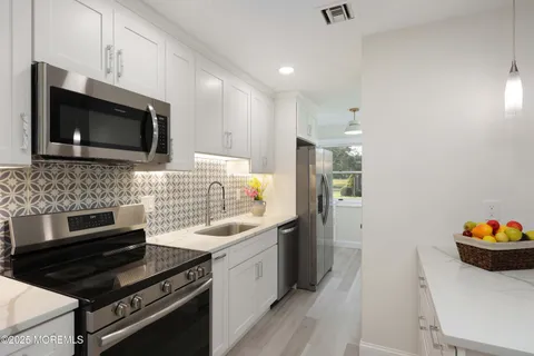 a kitchen with stainless steel appliances a sink a microwave a refrigerator and cabinets