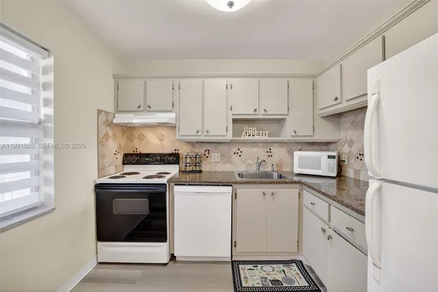 a kitchen with granite countertop white cabinets and white appliances