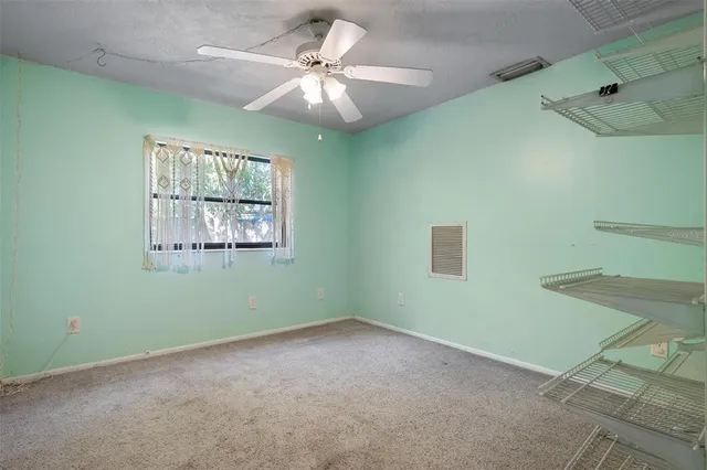 an empty room with a window and a fan