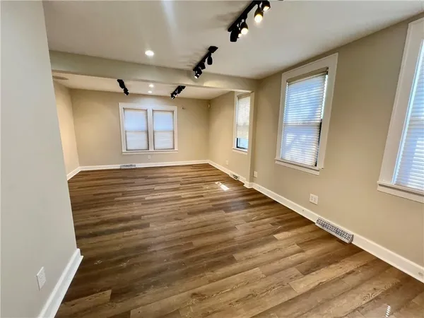 a view of an empty room with a window and wooden floor
