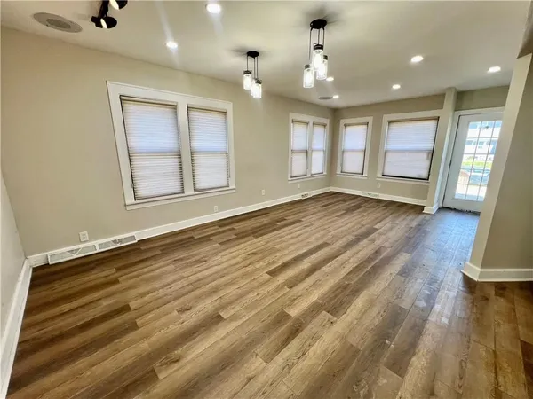 a view of an empty room with window and wooden floor