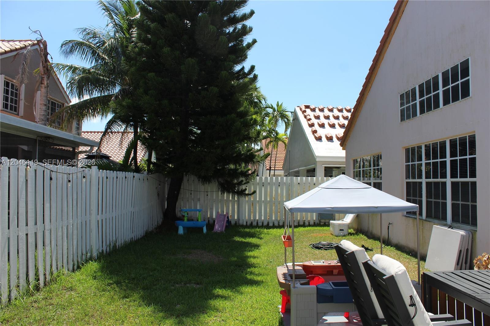312 Bridgeton Road Weston, FL 33326 - Photo 8 of 13 a view of a patio with a table and chairs under an umbrella with wooden fence