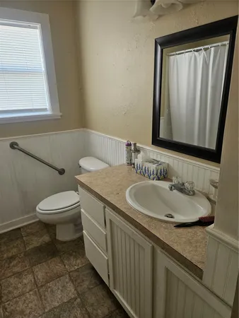 a bathroom with a granite countertop sink a toilet and a mirror
