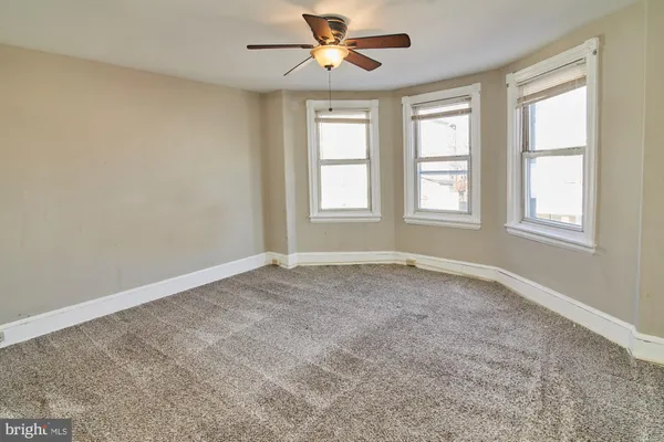 an empty room with windows and ceiling fan