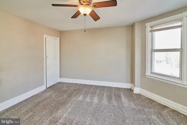 an empty room with a window and a fan