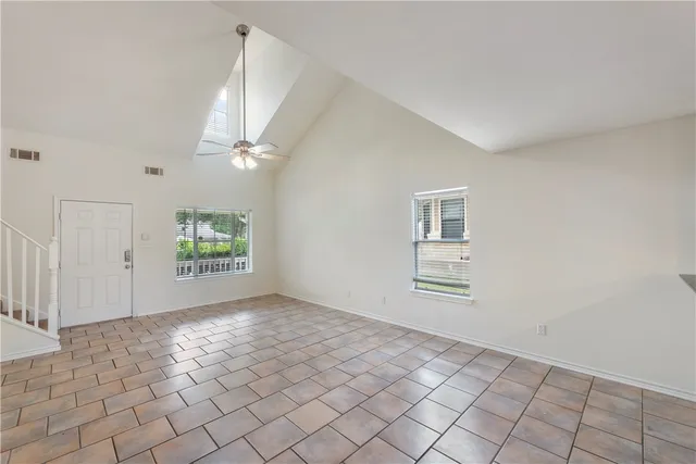 an empty room with windows and ceiling fan