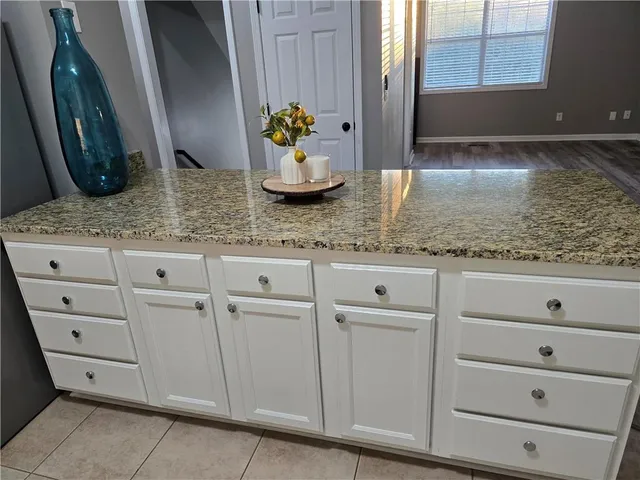 a kitchen with granite countertop white cabinets and a sink