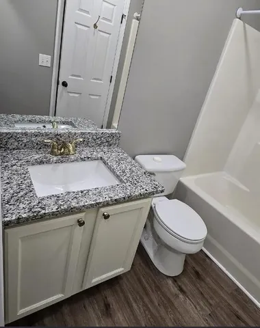 a bathroom with a granite countertop toilet a sink and a mirror
