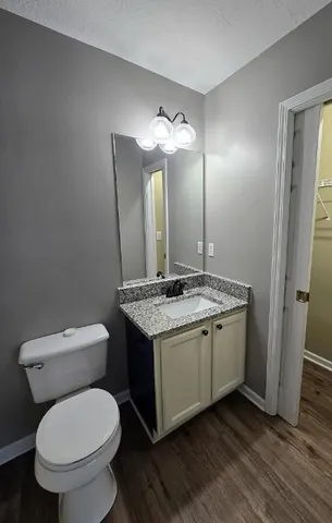 a bathroom with a granite countertop toilet a sink and a mirror