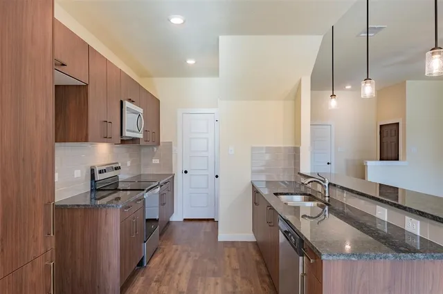 a kitchen with stainless steel appliances granite countertop a sink stove and refrigerator
