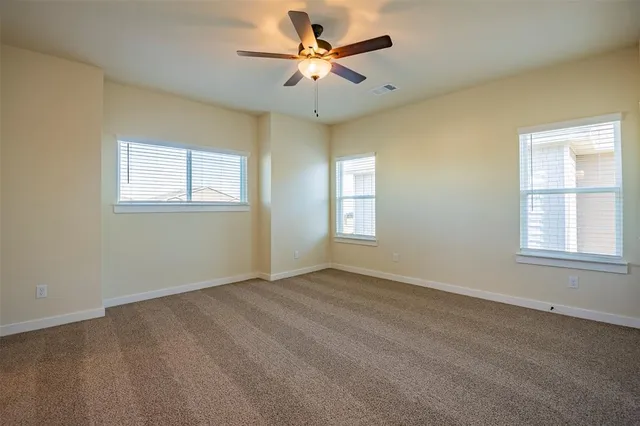 an empty room with windows and fan