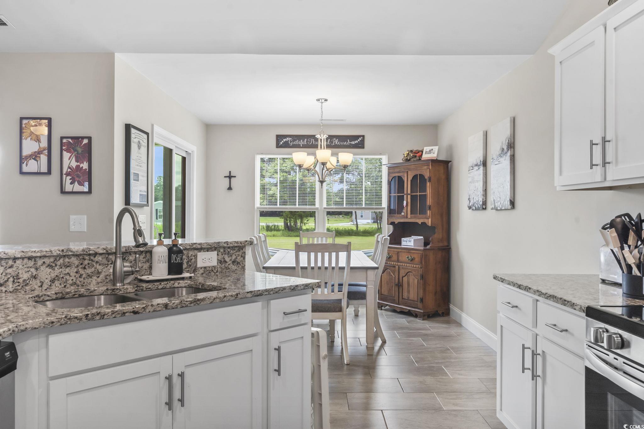 1170 Daisy Road Loris, SC 29569 - Photo 12 of 35 Kitchen with a chandelier, white cabinetry, light stone countertops, hanging light fixtures, and stainless steel stove