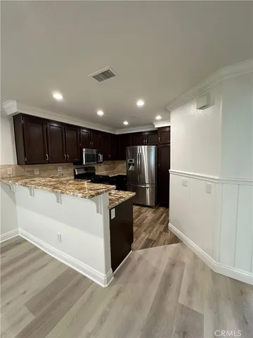 a view of kitchen with stainless steel appliances granite countertop a refrigerator and a stove top oven