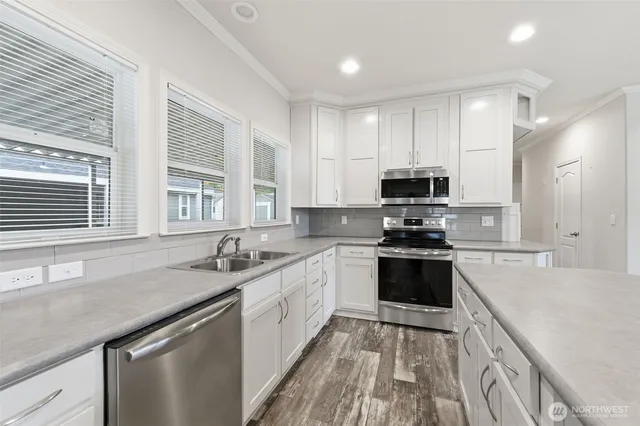 a kitchen with stainless steel appliances granite countertop a sink stove microwave and refrigerator