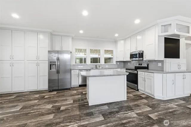 a kitchen with stainless steel appliances kitchen island granite countertop a refrigerator a stove top oven a sink and dishwasher