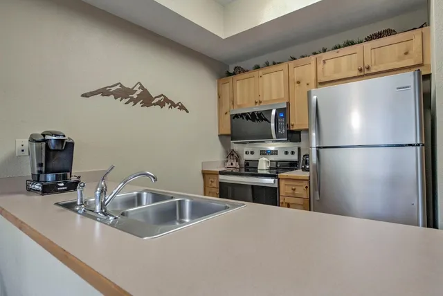 a kitchen with granite countertop a refrigerator stove and sink