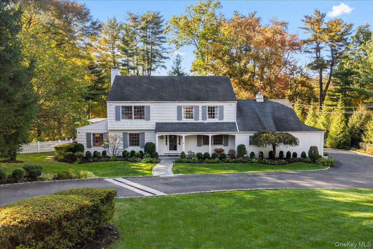 a front view of a house with a garden and trees