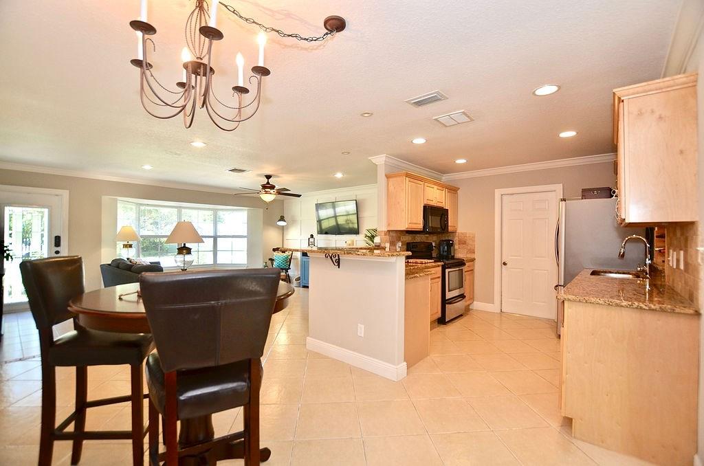 459 Southwest Byron Street Port St. Lucie, FL 34983 - Photo 13 of 51 a kitchen with a dining table chairs and a refrigerator